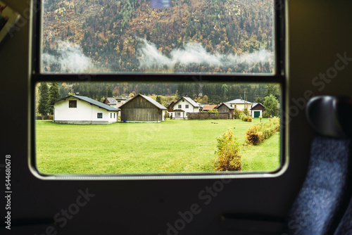 train view of houses in front of a lake surrounded by mountains