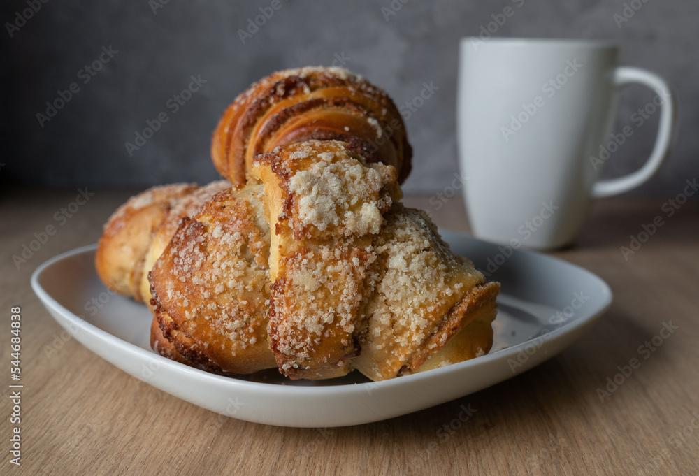 Fresh traditional polish pastry with poppy-seed filling and nuts. St. Martin's croissant. Rogal marciński or świętomarciński and white ceramic coffee cup or tea mug. Fresh traditional polish pastry with poppy-seed filling and nuts. St. Martin's croissant. Rogal marciński or świętomarciński and white ceramic coffee cup or tea mug.
