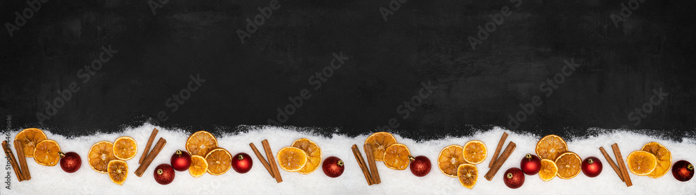 Fototapeta premium Christmas advent celebration holidays background banner panorama greeting card - Frame made of ornaments, red baubles, orange slices, cinnamon sticks and snow on concrete table, top view