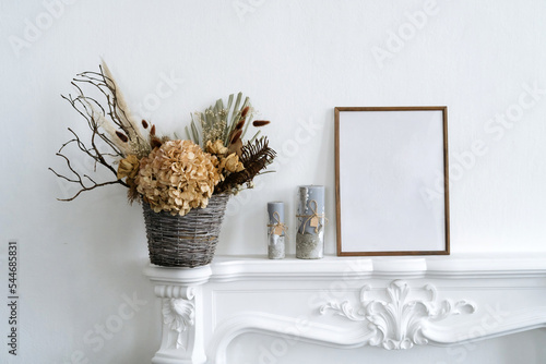 Elegant home interior in white tones under fireplace decorated beautiful dried flower comosition. photo