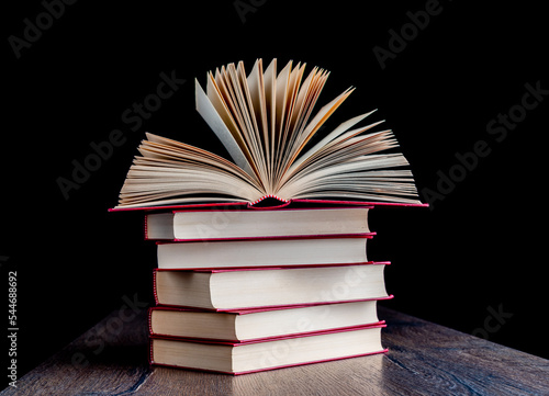 Stack of red-bound paper books on a wooden table.