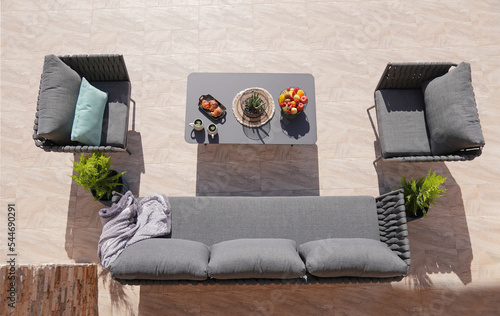 3 gray sofa and a table made of metal in the courtyard and garden on the garden tiles,comfortable sofa,shot from above