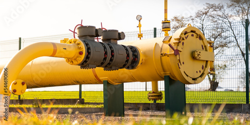 Big gas pipe - natural gas transport system. Transmission infrastructure coming from the ground, yellow pipes with a safety valve