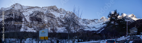 Beautiful winter panorama with fresh powder snow. Landscape with fir trees, blue sky with sunlight and high alpine mountains in the background The beautiful winter landscape with trees covered with ho photo