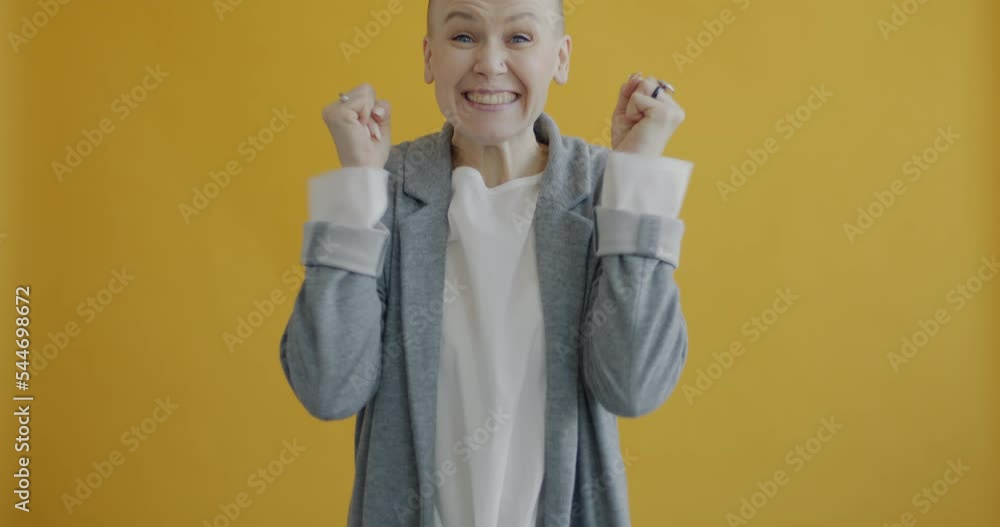 Slow motion portrait of excited lady screaming and raising arms enjoying good news on yellow background. Positivity and joyful people concept. Slow motion portrait of excited lady screaming and raising arms enjoying good news on yellow background. Positivity and joyful people concept.