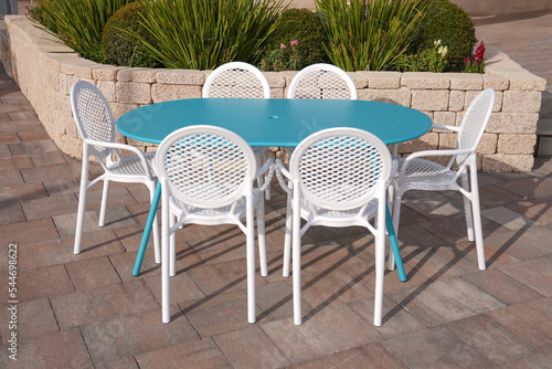 blue metal table with 6 white plastic chairs in the garden of the house  elegant luxury 