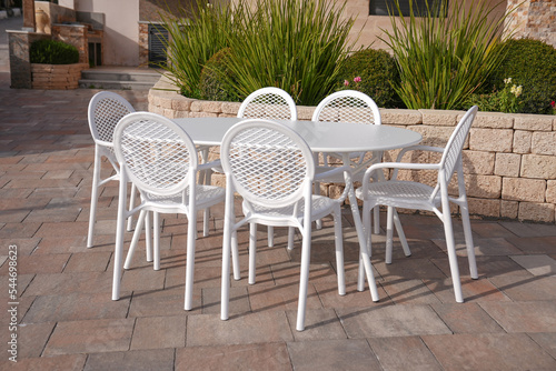 white metal table with 6 white plastic chairs in the garden of the house  elegant luxury 