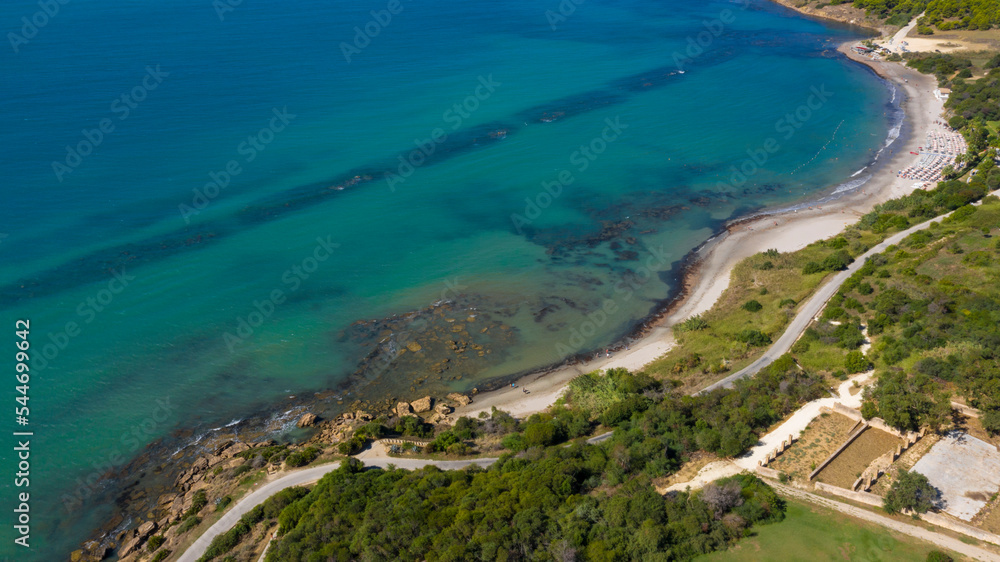 Aerial view of the Sicilian coast overlooking the Mediterranean sea, in Italy. The sea is turquoise and the beach is sandy. There is no one in the water or on the coast.
