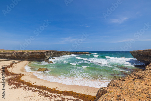 Beautiful view of waves of Atlantic Ocean breaking on rocky shore in lagoon. Aruba.