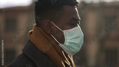 African male walking outside during winter wearing covid surgical face mask outside2 photo