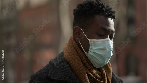 African male walking outside during winter wearing covid surgical face mask outside2 photo