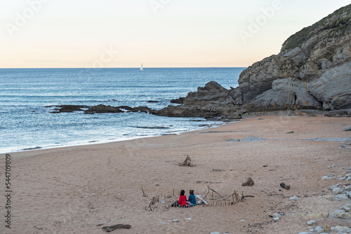 Two young people relax at sunrise on the beach