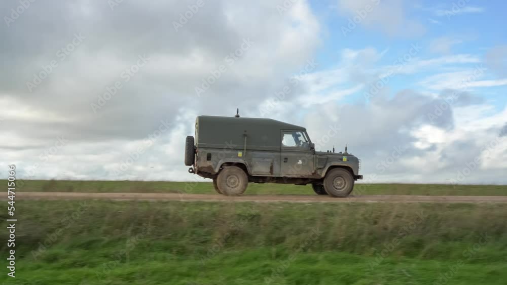 two British army Wolf 4x4 medium utility vehicles pass at speed on a mud track, military exercise Wilts UK two British army Wolf 4x4 medium utility vehicles pass at speed on a mud track, military exercise Wilts UK