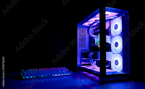 Water Cooled Gaming Pc with RGB rainbow LED lighting. Modern gaming computer with a keyboard in a dark room. Water Liquid Cooling Computer.
