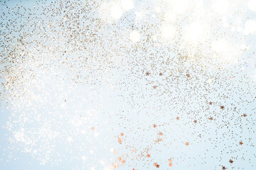 Beautiful Christmas light background. Abstract glitter bokeh and scattered sparkles in gold, on black