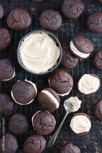 Filling multiple chocolate whoopie pie cookies with marshmallow cream filling.  