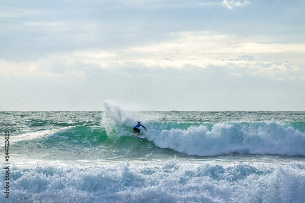 Fototapeta premium Gorgeous view on urfer ride the wave, many splashes in sunbeams on surfing competetion Moche Rip Curl Pro Portugal 2015