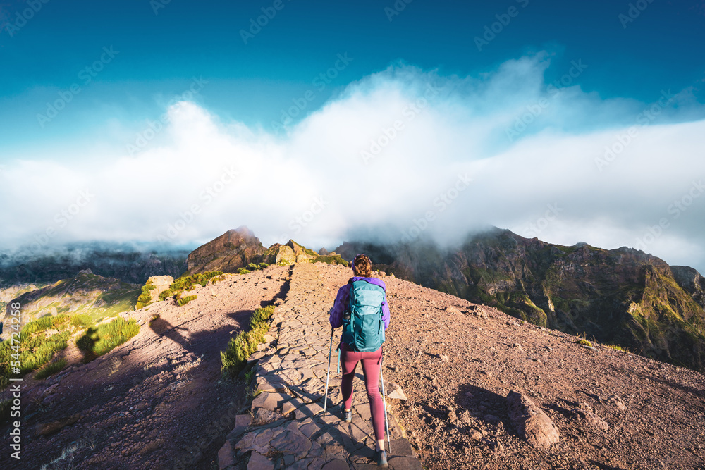 Woman hiking along scenic hike trail to Pico Ruivo in the morning. Pico do Arieiro, Madeira Island, Portugal, Europe.