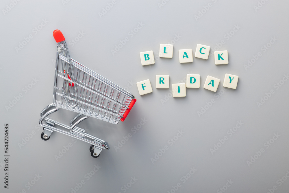 Black friday text and shopping cart on gray background. Top view. - obrazy, fototapety, plakaty 