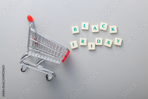 Foto Black friday text and shopping cart on gray background. Top view.