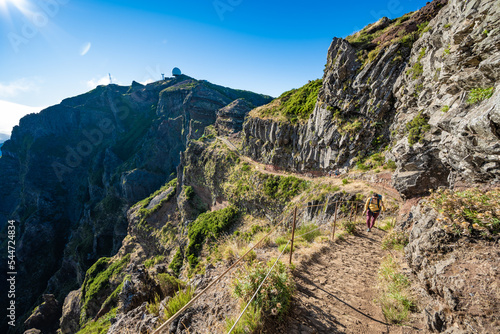 Woman hiking along scenic hike trail to Pico Ruivo in the morning. Pico do Arieiro, Madeira Island, Portugal, Europe.
