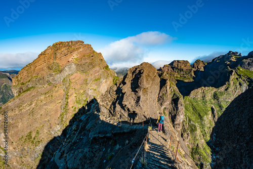 Woman hiking down steep stairs along scenic hike trail to Pico Ruivo in the morning. Pico do Arieiro, Madeira Island, Portugal, Europe.