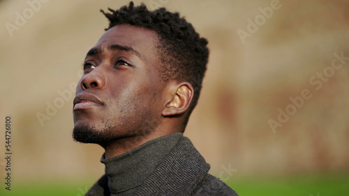 African young black man standing at park looking up in contemplation2