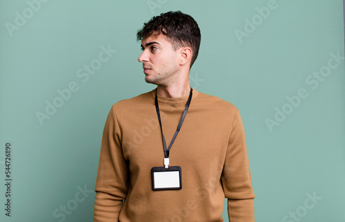 adult man on profile view thinking, imagining or daydreaming with an acccess identity card photo