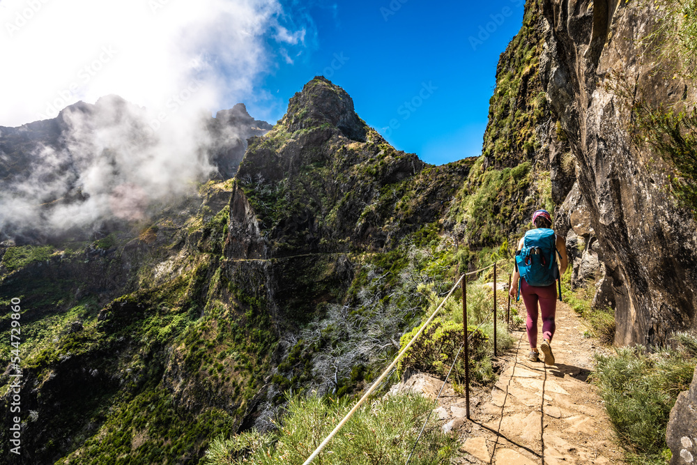 Hiker with backpack walking along very scenic hike trail to Pico do Ariero in the afternoon. Verade do Pico Ruivo, Madeira Island, Portugal, Europe.