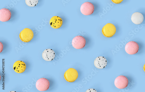 Many different macaroons pattern on blue background. Pink  white and yellow French cookies. Strawberry  black currant and blueberry  lemon and lime vanilla meringue dessert