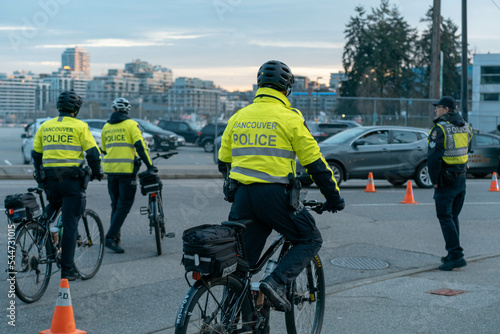 Vancouver Canada - November 21, 2021: A Vancouver police officer on a bike patrols near Downtown Vancouver with the city skyline in the background