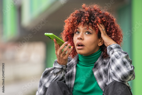 girl sending voice message with mobile phone in the street