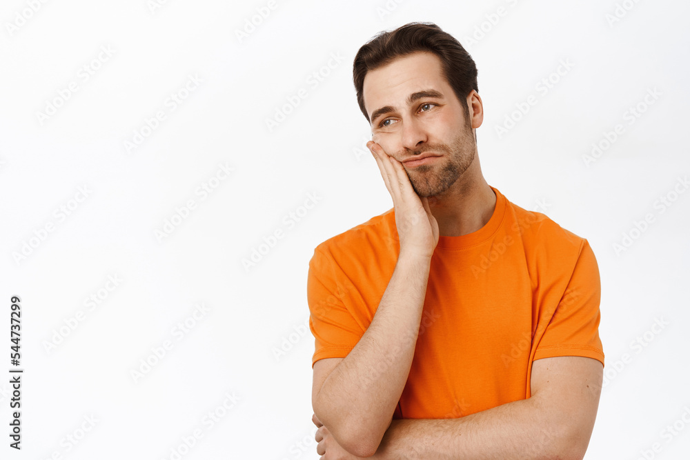 Man thinking, looking complicated, dreaming of smth, standing in orange tshirt over white background Man thinking, looking complicated, dreaming of smth, standing in orange tshirt over white background