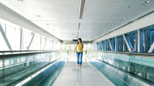 Woman walking between Automatic walkways, in subway crossing, using her phone, a mean of communication, a fashionable gadget. The concept is always in touch. High quality photo