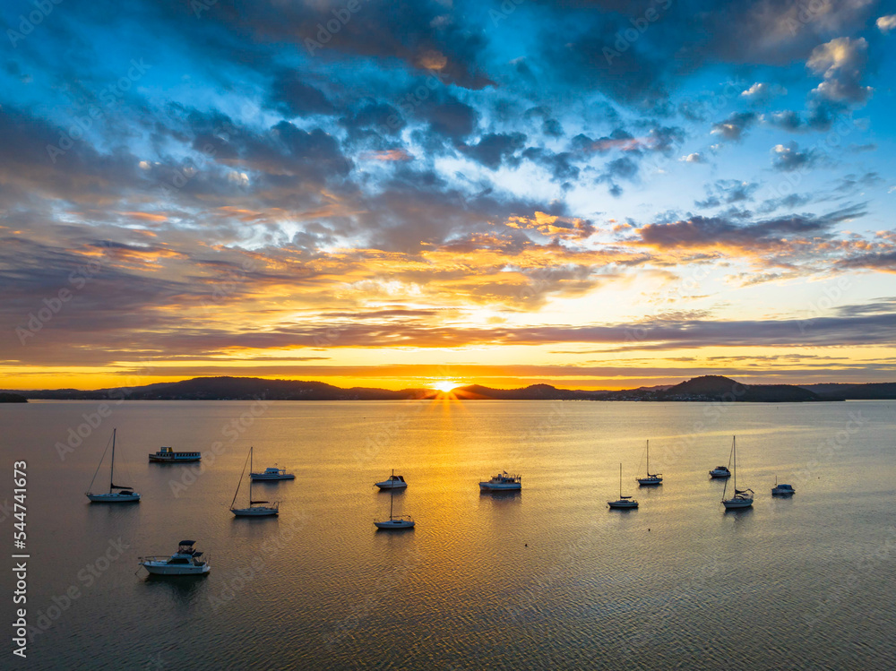 Aerial sunrise over the bay with boats, clouds and sunburst