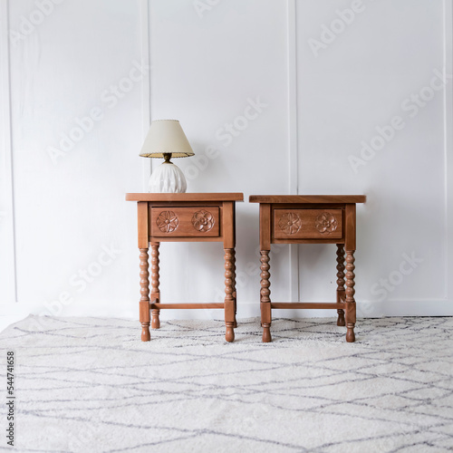 Front view of a picturesque pair of bed tables in a bright and white room illuminated under natural lighting