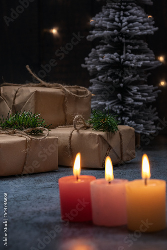 christmas gifts on the tree, behind candles, concept waiting for christmas
