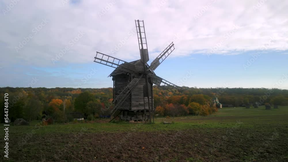 Drone flight low above the grass to old wooden windmill in autumn day Drone flight low above the grass to old wooden windmill in autumn day