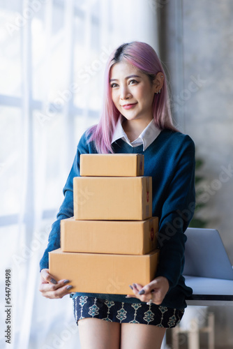 Young entrepreneur, teenager Asian business owner work with SME boxs at homeworkplace, freelance start-up small business entrepreneur SME online business and delivery concept. © David