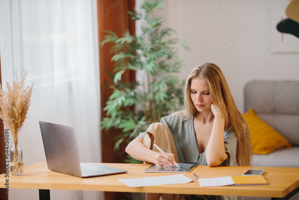 Female graphic designer working at home with digital drawing tablet and pen. Female graphic designer working at home with digital drawing tablet and pen.
