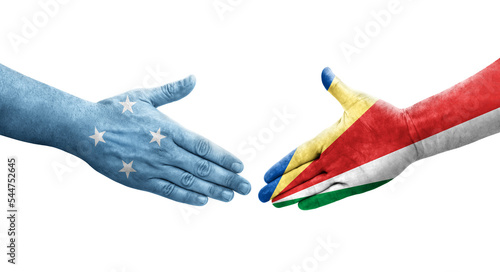 Handshake between Micronesia and Seychelles flags painted on hands, isolated transparent image.