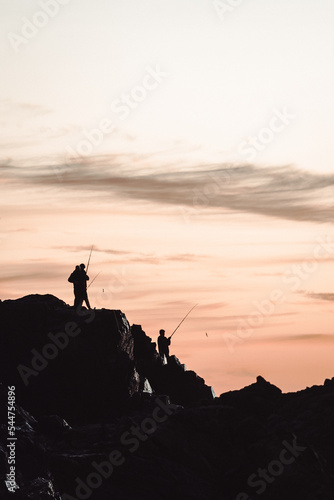 silhouette of a person on a rock fishing