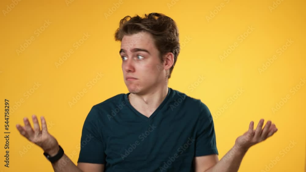 Portrait of happy young man 20s shrugging shoulders and gesturing I do not know isolated on yellow background. Portrait of happy young man 20s shrugging shoulders and gesturing I do not know isolated on yellow background.