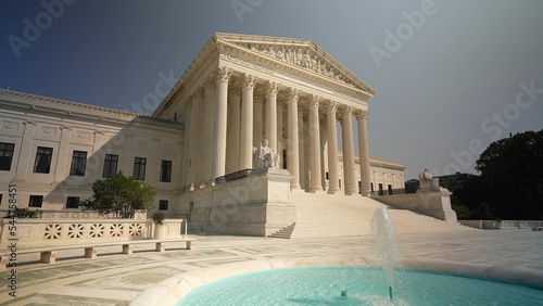 Facade of US Supreme Court building with Authority of Justice sculpture in front in Washington DC on a sunny summer evening.