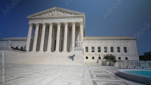 Wide angle view of facade of US Supreme Court building with Authority of Justice sculpture in front on a sunny summer day.