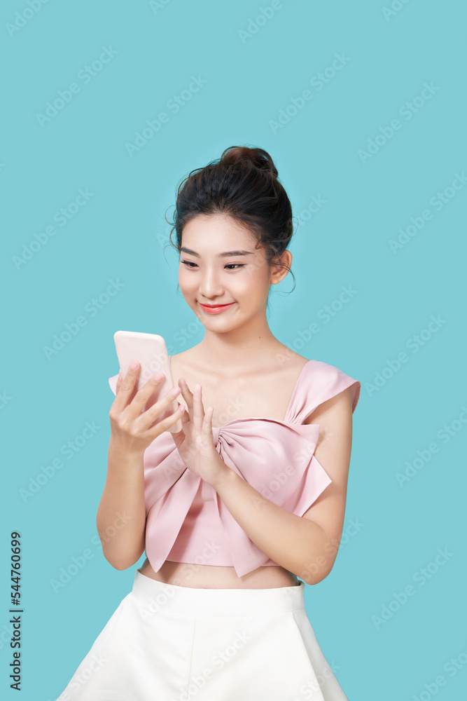 Portrait of a smiling casual woman holding smartphone over blue background Portrait of a smiling casual woman holding smartphone over blue background