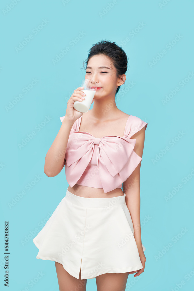 Beautiful young woman drinking milk on blue background Beautiful young woman drinking milk on blue background