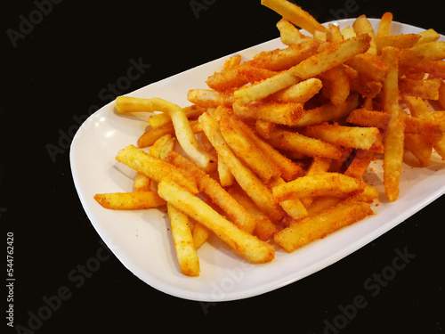 French fries in white plate on black table