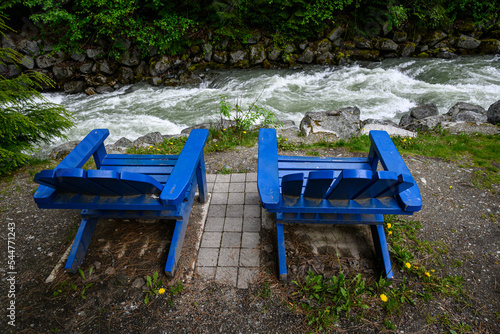 Bright blue Adirondack chairs on the bank of Fitzsimmons Creek, Whistler, BC, Canada
 photo