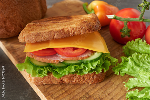 Meat and vegetable sandwich on wood with tomatoes and bell peppers. 
